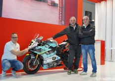 Vanni Vignali ci mostra il dettaglio del marchio Vignali su questa motocicletta da corsa. Accanto a lui, Fabio Vignali e Samuele Zanelli.