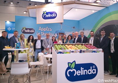 Una foto di gruppo presso lo stand Melinda. Sullo sfondo, un'immagine della "funivia delle mele": composta da 11 piloni e 28 cabine, ciascuna in grado di trasportare fino a 3 bins per viaggio, ha una velocità operativa è di 5 m/s per una capacità stimata fino a 150 tonnellate/ora. Il tracciato, lungo 1340 metri, supera un dislivello di circa 90 metri e prosegue per altri 450 metri in galleria fino al collegamento con le celle ipogee.