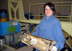 Una delle lavoratrici addette al confezionamento carica la cassetta sul nastro del macchinario pallettizzatore.