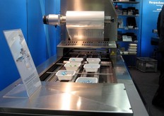 Macchina confezionatrice di vassoi della ALX. Il film non viene semplicemente tagliato dal rotolo, ma e' tagliato lungo i contorni del vassoio.