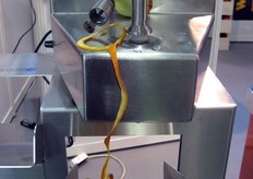 Nel dettaglio vediamo la pelatura di un'arancia. I frutti vengono fatti ruotare sul loro asse tramite un tridente inferiore e vengono fissati tramite un puntale mobile nella parte superiore. Possono essere sbucciati frutti fino a un'altezza massima di 120mm. Un braccio mobile segue la superficie del frutto e si ferma automaticamente a fine ciclo.