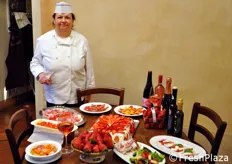 Chef Rita Soverini in posa accanto ad uno dei tavoli allestiti con le sue preparazioni culinarie.