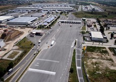 "Veduta aerea del piazzale d'ingresso con, sullo sfondo a sinistra, i due padiglioni "Est" e "Ovest" dedicati al Mercato Ortofrutticolo. Qua e la', tra gli edifici, si notano le pensiline fotovoltaiche a copertura dei parcheggi. Foto: Archivio CAR."