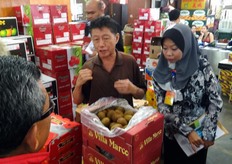 Un espositore del mercato presenta alla delegazione il kiwi che importa dall'Italia.