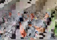 Muniti di cuffie e camice, il gruppo entra nel magazzino di lavorazione.