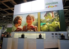 Le teche che nello stand sudtirolese mostrano le mele- gioiello. Dietro scene di 'vita ordinaria' nel Sud Tirolo: la raccolta delle mele, bambini e sugli altri lati dello stand anche i melicoltori: una mela e' il suo territorio.